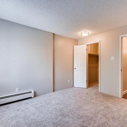 Carpeted bedroom with a view of bedroom and closet at The Oslo, located in Northglenn, CO