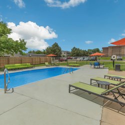 Swimming pool with lounge chairs and unbrellas at The Oslo, located in Northglenn, CO