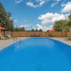 Swimming pool with lounge chairs and unbrellas at The Oslo, located in Northglenn, CO 2