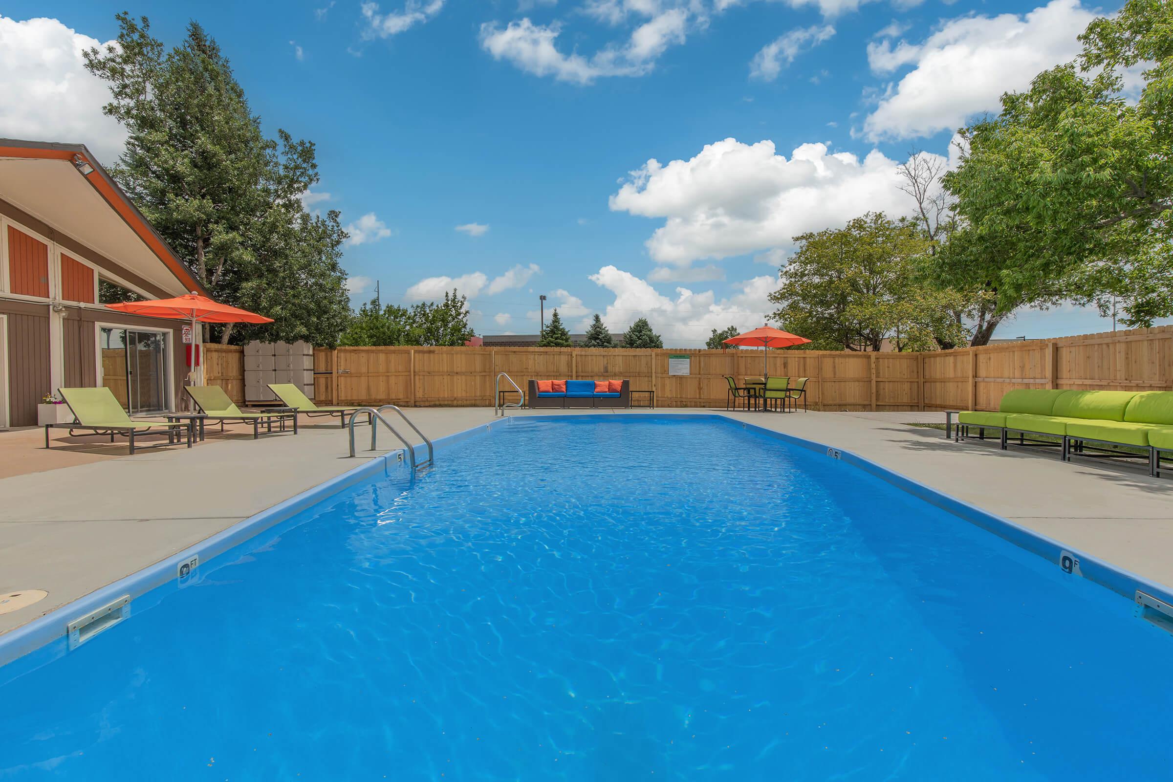 Swimming pool with lounge chairs and unbrellas at The Oslo, located in Northglenn, CO 2