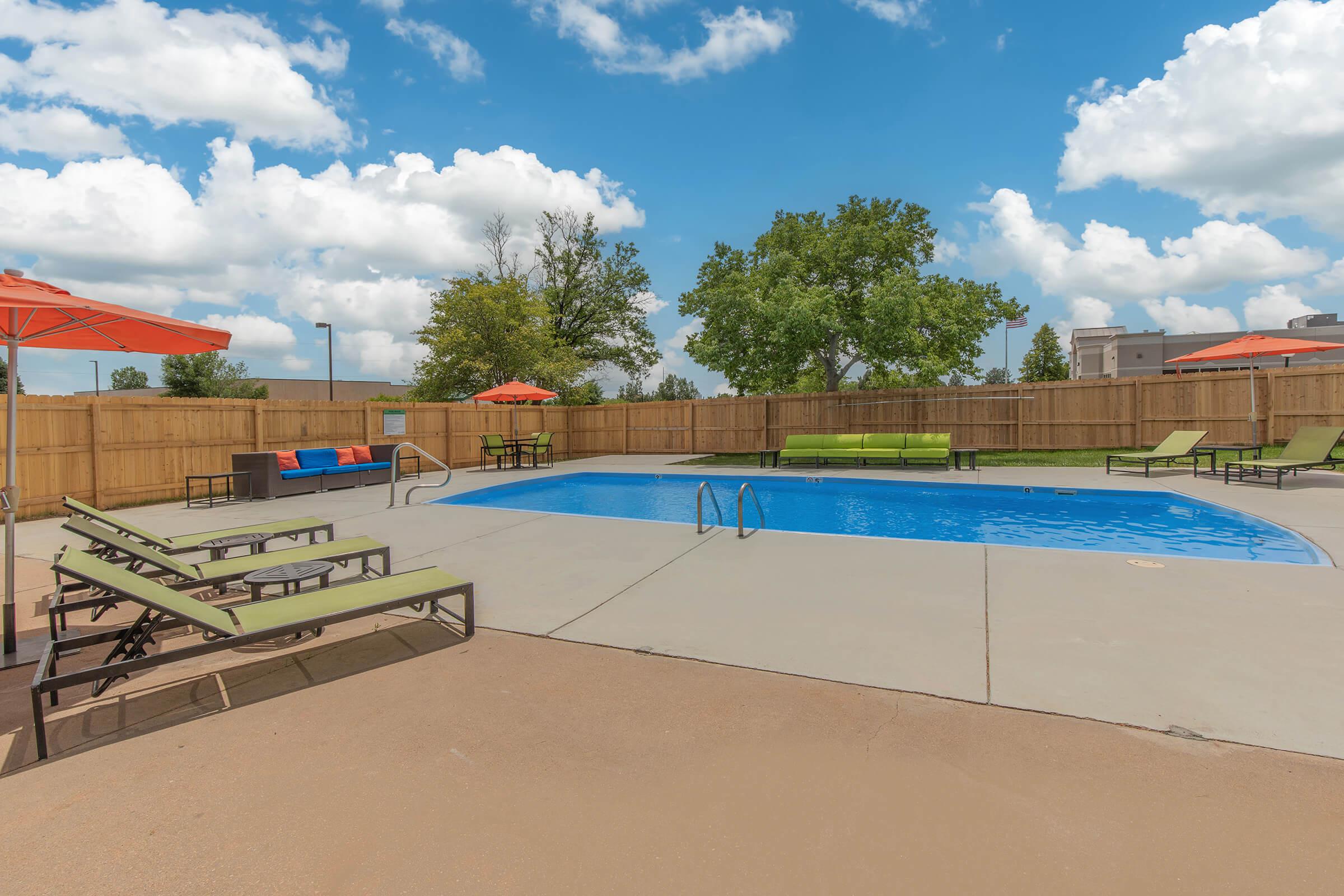 Swimming pool with lounge chairs and umbrellas at The Oslo, located in Northglenn, CO